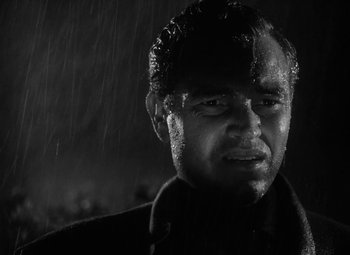 Movie still from “Detour” (1945), directed by Edgar G. Ulmer – Black and white photograph of a man in the rain; Close Up shot, Low angle