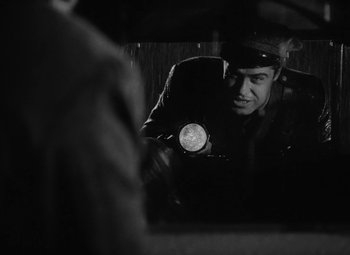 Movie still from “Detour” (1945), directed by Edgar G. Ulmer – A man looking at himself in the mirror holding a flashlight; Medium shot, Over the shoulder angle