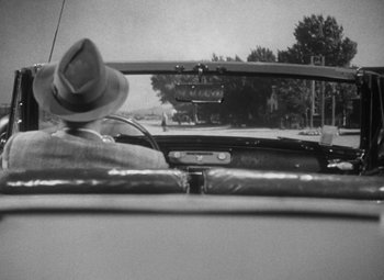 Movie still from “Detour” (1945), directed by Edgar G. Ulmer – A black - and - white photo of a hat on the dashboard of a car; Close Up shot, Over the shoulder angle