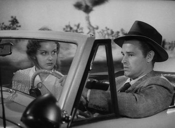 Movie still from “Detour” (1945), directed by Edgar G. Ulmer – A man and a woman sitting in the drivers seat of a car; Medium shot, Low angle