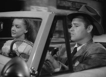 Movie still from “Detour” (1945), directed by Edgar G. Ulmer – A man and a woman driving a car in the back of a car; Medium shot, High angle