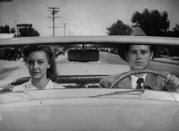 Movie still from “Detour” (1945), directed by Edgar G. Ulmer – A man and a woman sitting in the back seat of a car; Medium shot, Low angle