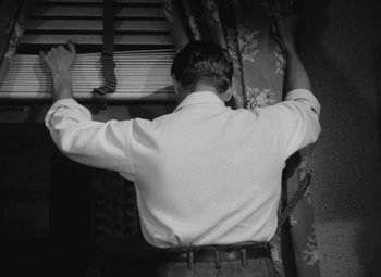 Movie still from “Detour” (1945), directed by Edgar G. Ulmer – A black and white photo of a man looking out of a window; Medium shot, Low angle