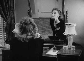 Movie still from “Detour” (1945), directed by Edgar G. Ulmer – A woman sitting in front of a mirror looking at herself in the mirror; Medium shot, Over the shoulder angle