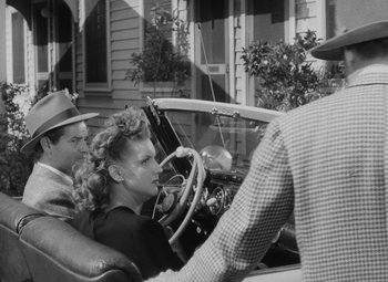 Movie still from “Detour” (1945), directed by Edgar G. Ulmer – A man and a woman driving a car in the street; Medium shot, High angle