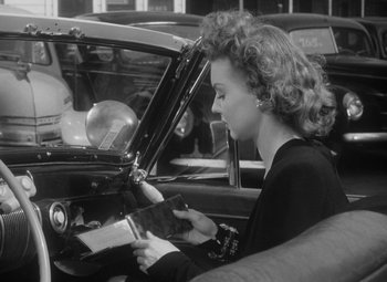 Movie still from “Detour” (1945), directed by Edgar G. Ulmer – A black and white photo of a woman sitting in a car; Medium shot, Low angle
