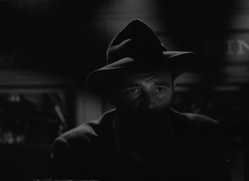 Movie still from “Detour” (1945), directed by Edgar G. Ulmer – A black and white photo of a man wearing a hat; Close Up shot, Low angle