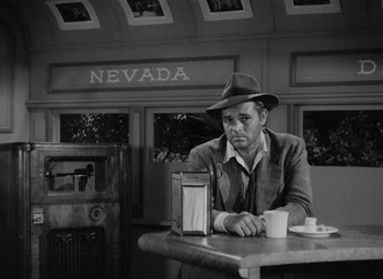 Movie still from “Detour” (1945), directed by Edgar G. Ulmer – A black and white photo of a man sitting at a table; Medium shot, Low angle