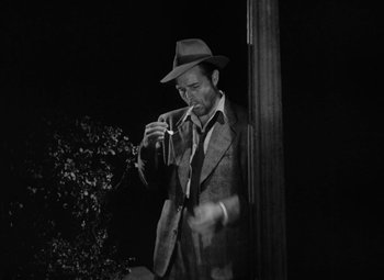 Movie still from “Detour” (1945), directed by Edgar G. Ulmer – A black and white photo of a man smoking a cigarette; Medium shot, Low angle