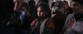 Movie still from “Dheepan” (2015), directed by Jacques Audiard – A young girl sitting in front of a group of people; Close Up shot, Over the shoulder angle
