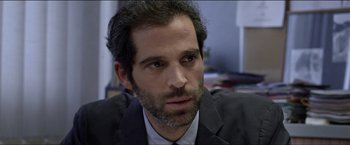 Movie still from “Dheepan” (2015), directed by Jacques Audiard – A person wearing a suit and tie; Close Up shot, Over the shoulder angle