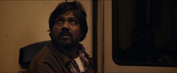 Movie still from “Dheepan” (2015), directed by Jacques Audiard – A person sitting on a train; Close Up shot, Over the shoulder angle