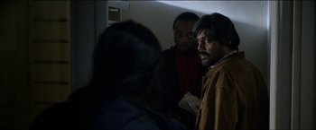 Movie still from “Dheepan” (2015), directed by Jacques Audiard – A group of men standing next to each other in a room; Medium shot, Over the shoulder angle