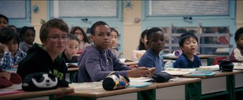 Movie still from “Dheepan” (2015), directed by Jacques Audiard – A group of children sitting at a table in a classroom; Medium shot, Over the shoulder angle