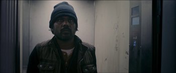Movie still from “Dheepan” (2015), directed by Jacques Audiard – A man wearing a hat standing in front of a wall; Close Up shot, Low angle