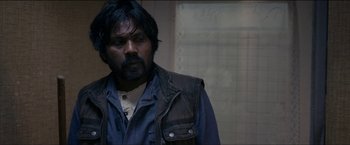Movie still from “Dheepan” (2015), directed by Jacques Audiard – A man with a beard wearing a leather vest; Close Up shot, Over the shoulder angle
