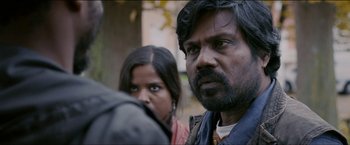 Movie still from “Dheepan” (2015), directed by Jacques Audiard – A man and a woman standing next to each other in front of a tree; Close Up shot, Over the shoulder angle