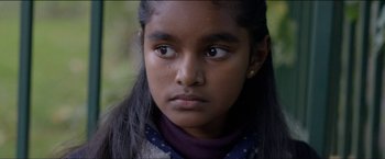 Movie still from “Dheepan” (2015), directed by Jacques Audiard – A young girl is looking into the camera; Close Up shot, Over the shoulder angle