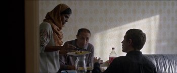Movie still from “Dheepan” (2015), directed by Jacques Audiard – A man sitting at a table with a plate of food on top of it; Medium shot, Over the shoulder angle