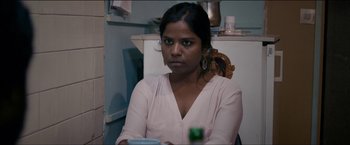 Movie still from “Dheepan” (2015), directed by Jacques Audiard – A woman sitting in front of a refrigerator holding a drink; Close Up shot, Over the shoulder angle