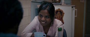 Movie still from “Dheepan” (2015), directed by Jacques Audiard – A woman sitting at a table with a cup of coffee; Close Up shot, Over the shoulder angle