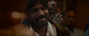 Movie still from “Dheepan” (2015), directed by Jacques Audiard – A person with a beard wearing a white shirt; Close Up shot, Over the shoulder angle