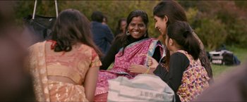 Movie still from “Dheepan” (2015), directed by Jacques Audiard – A group of people sitting around talking to each other; Medium shot, High angle