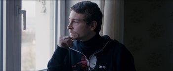 Movie still from “Dheepan” (2015), directed by Jacques Audiard – A young man wearing headphones looking out a window; Close Up shot, Over the shoulder angle