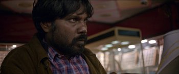 Movie still from “Dheepan” (2015), directed by Jacques Audiard – A person wearing a plaid shirt; Close Up shot, Over the shoulder angle