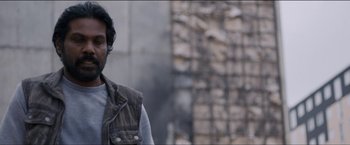 Movie still from “Dheepan” (2015), directed by Jacques Audiard – A man standing in front of a brick wall; Close Up shot, Over the shoulder angle