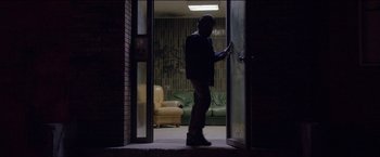 Movie still from “Dheepan” (2015), directed by Jacques Audiard – A man standing at the door of a living room at night; Wide shot, Low angle