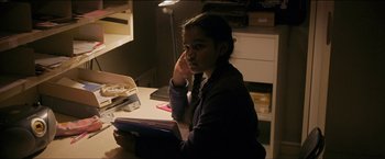 Movie still from “Dheepan” (2015), directed by Jacques Audiard – A girl sitting at a desk with a book in her hand; Medium shot, Over the shoulder angle