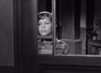 Movie still from “Diabolique” (1955), directed by Henri-Georges Clouzot – A young boy looking out of a window; Medium shot, High angle