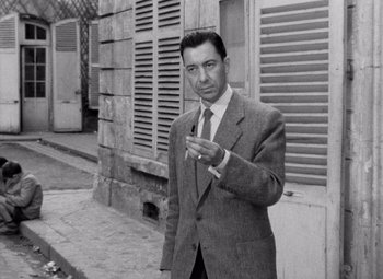 Movie still from “Diabolique” (1955), directed by Henri-Georges Clouzot – A black and white photo of a man wearing a suit and tie; Medium shot, Low angle