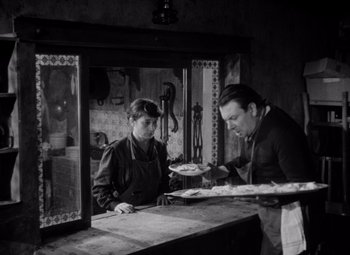 Movie still from “Diabolique” (1955), directed by Henri-Georges Clouzot – A man and a woman are standing at a counter; Medium shot, High angle