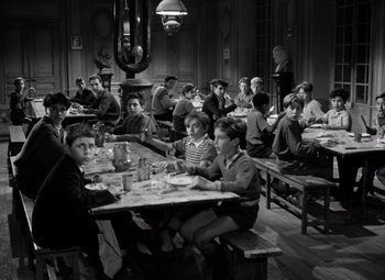 Movie still from “Diabolique” (1955), directed by Henri-Georges Clouzot – A group of people sitting at a table eating; Wide shot, High angle