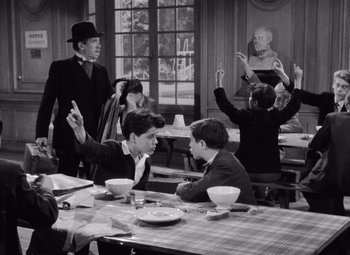 Movie still from “Diabolique” (1955), directed by Henri-Georges Clouzot – A black and white photo of a group of young men sitting at a table; Medium shot, Over the shoulder angle