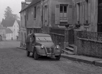 Movie still from “Diabolique” (1955), directed by Henri-Georges Clouzot – An old black and white photo of a car parked on the side of the road; Extreme Wide shot, High angle