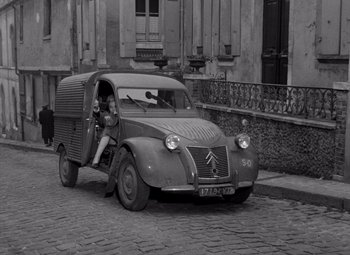 Movie still from “Diabolique” (1955), directed by Henri-Georges Clouzot – An old photo of an old car parked on the side of the road; Wide shot, High angle