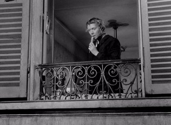 Movie still from “Diabolique” (1955), directed by Henri-Georges Clouzot – A woman standing on a balcony looking out of a window; Medium shot, Low angle
