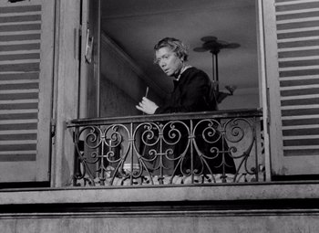 Movie still from “Diabolique” (1955), directed by Henri-Georges Clouzot – A man standing on a balcony looking out of a window; Medium shot, High angle