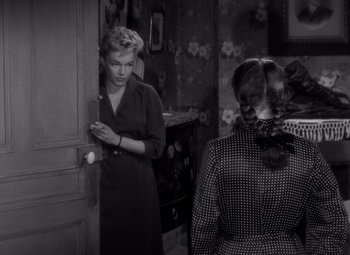 Movie still from “Diabolique” (1955), directed by Henri-Georges Clouzot – Two women are standing in the doorway of a house; Medium shot, High angle