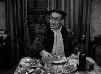 Movie still from “Diabolique” (1955), directed by Henri-Georges Clouzot – An older man sitting at a table with a plate of food; Medium shot, High angle