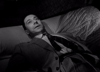 Movie still from “Diabolique” (1955), directed by Henri-Georges Clouzot – A black and white photo of a man in a suit and tie; Close Up shot, Overhead angle