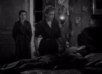 Movie still from “Diabolique” (1955), directed by Henri-Georges Clouzot – A woman standing next to a man in a bed; Medium shot, High angle