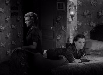 Movie still from “Diabolique” (1955), directed by Henri-Georges Clouzot – Two women sitting on a couch in a living room; Medium shot, High angle
