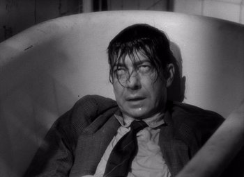 Movie still from “Diabolique” (1955), directed by Henri-Georges Clouzot – A black and white photo of a man in a suit and tie; Close Up shot, High angle