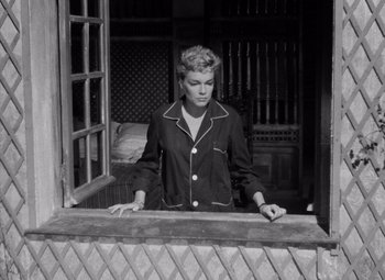 Movie still from “Diabolique” (1955), directed by Henri-Georges Clouzot – A black and white photo of a woman looking out of a window; Medium shot, High angle