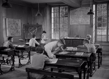 Movie still from “Diabolique” (1955), directed by Henri-Georges Clouzot – A group of people sitting at tables in a room; Wide shot, High angle
