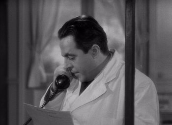 Movie still from “Diabolique” (1955), directed by Henri-Georges Clouzot – A black and white photo of a man talking on a phone; Close Up shot, High angle